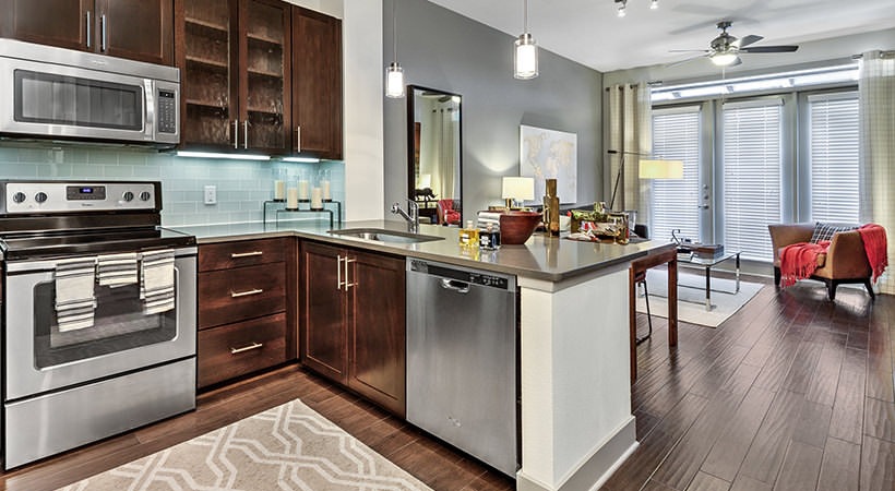 a kitchen with stainless steel appliances and wood floors at The Teak at  Branch