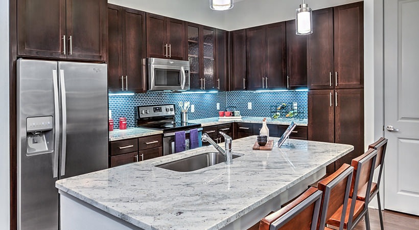 a kitchen with stainless steel appliances and granite counter tops at The Teak at  Branch