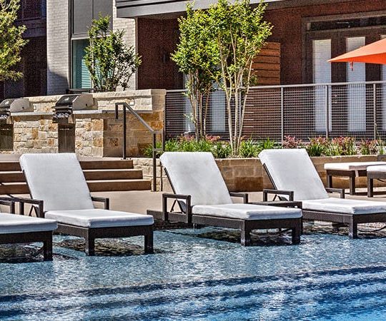 a pool with lounge chairs and umbrellas at The Teak at  Branch